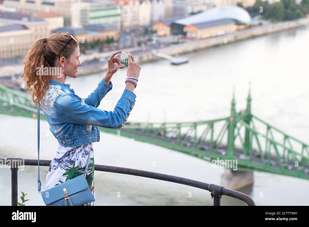 Donna che fotografa Liberty Bridge dalla Cittadella a Budapest, Ungheria Foto Stock
