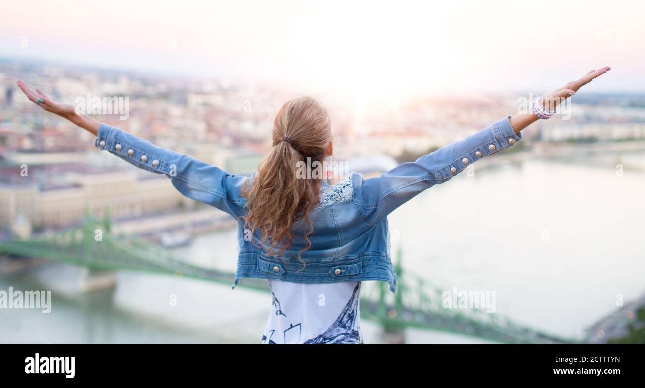 Giovane donna che alza le armi in città alba, Budapest, Ungheria Foto Stock