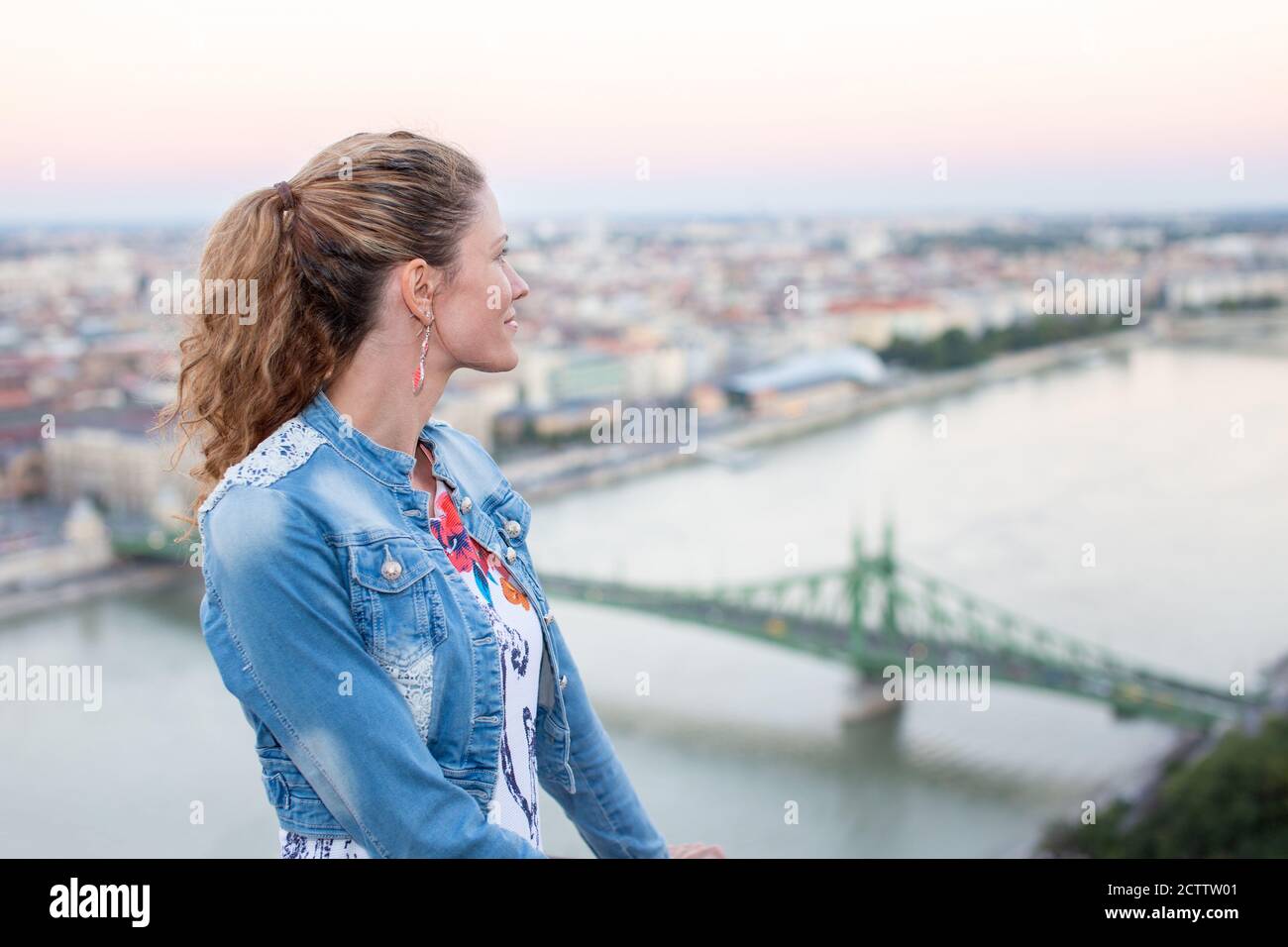 Giovane donna che si chiede a Budapest panorama da Citadella, Ponte della libertà con il Danubio, Ungheria Foto Stock
