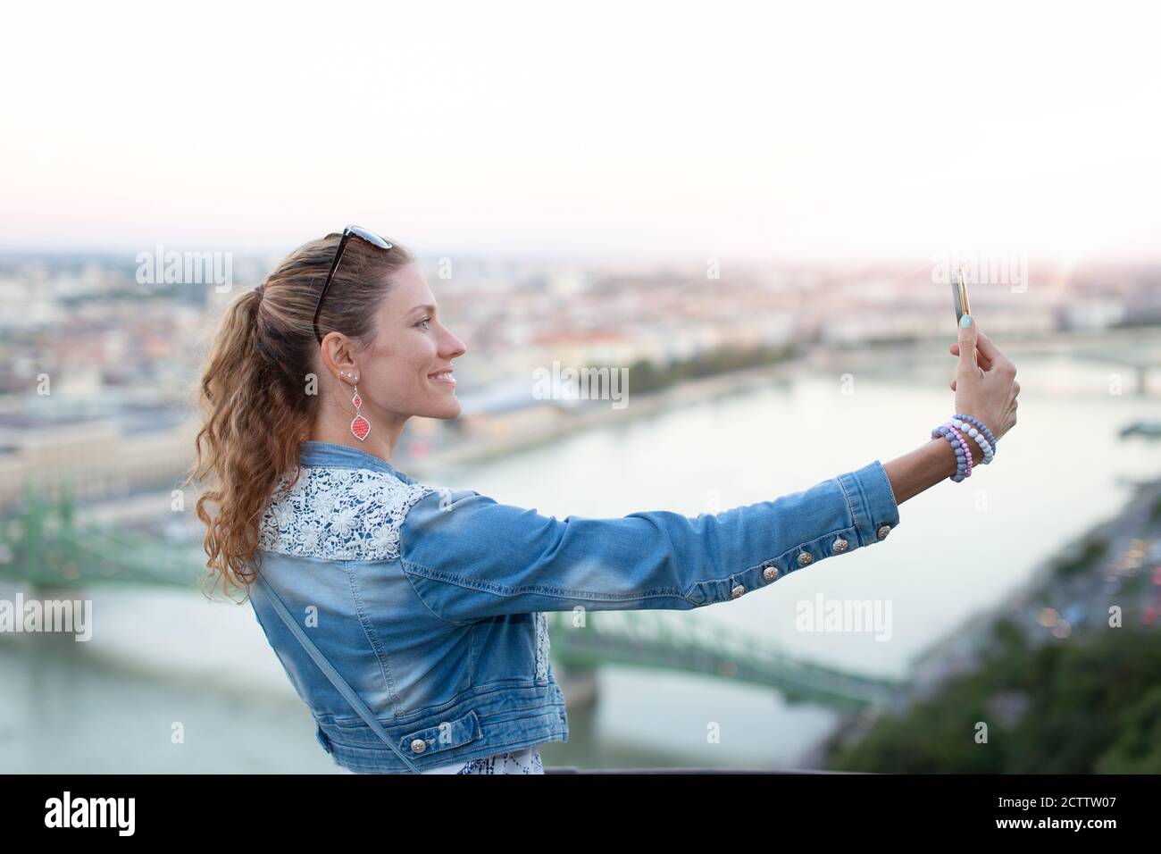 Felice giovane donna turistica che prende selfie con panorama della città, Budapest, Ungheria Foto Stock