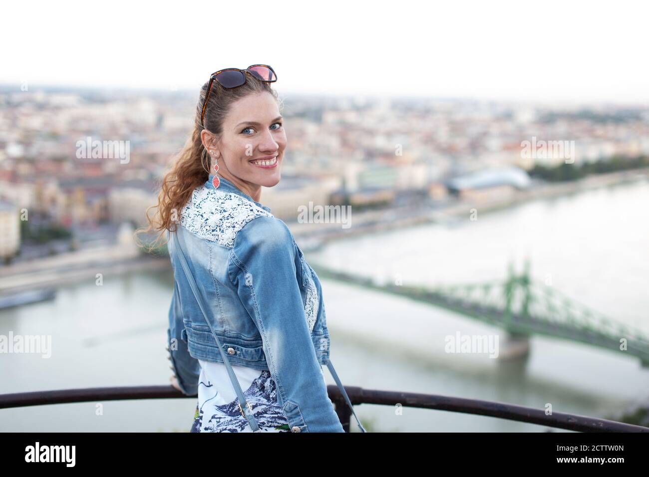 Felice giovane donna che guarda indietro al panorama della città, Budapest, Ungheria Foto Stock