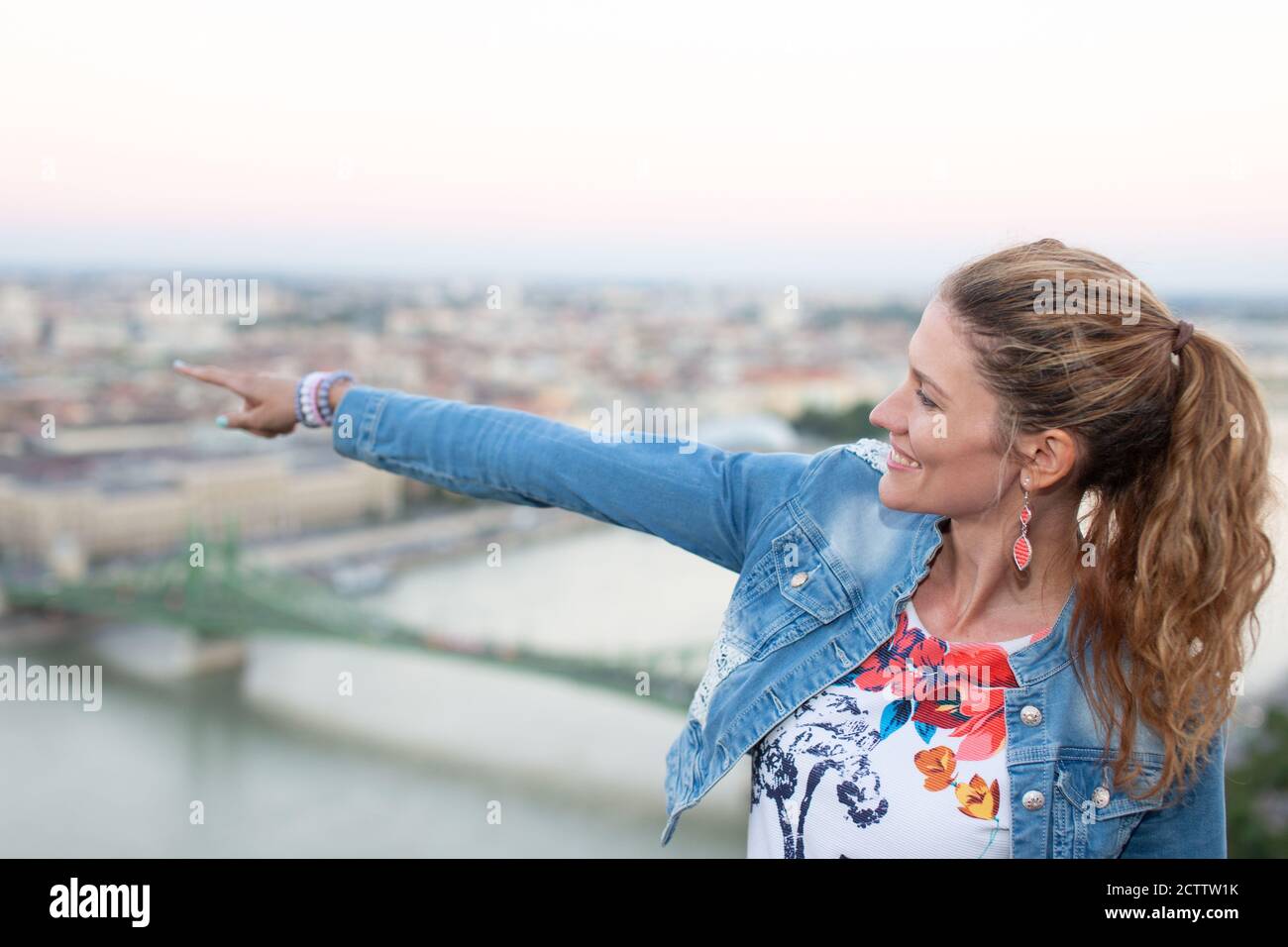 Giovane donna allegra che indica il posto famoso durante il viaggio di Budapest, Ungheria Foto Stock