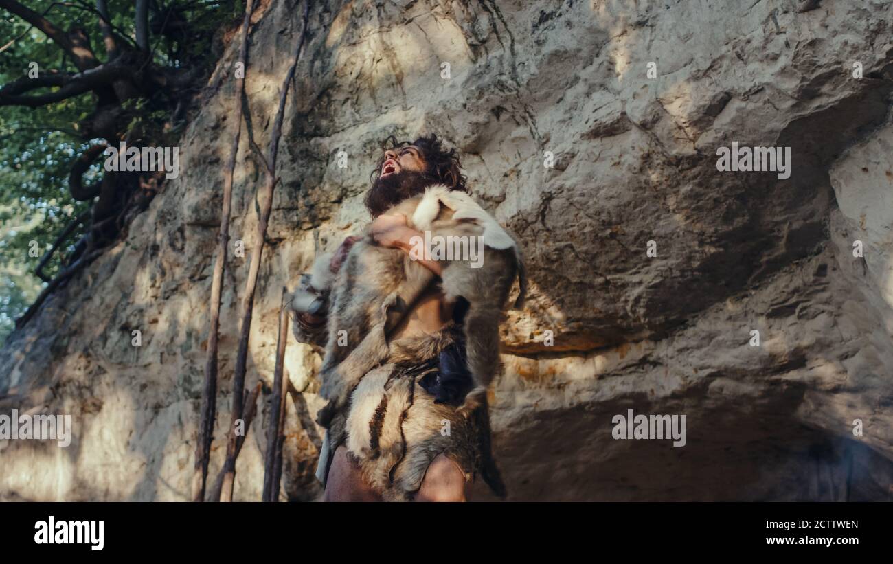 Ritratto di Primeval Caveman indossare la pelle animale fa aggressivo Chest battendo e Screaming, difensore la sua grotta e territorio nella preistoria Foto Stock