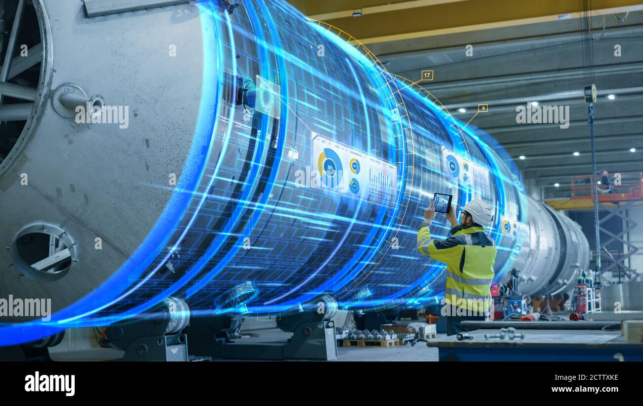 Concetto AR: L'ingegnere industriale utilizza il tablet digitale con realtà aumentata per eseguire la scansione di grandi costruzioni metalliche, visualizzazione di spettacoli con effetti speciali Foto Stock