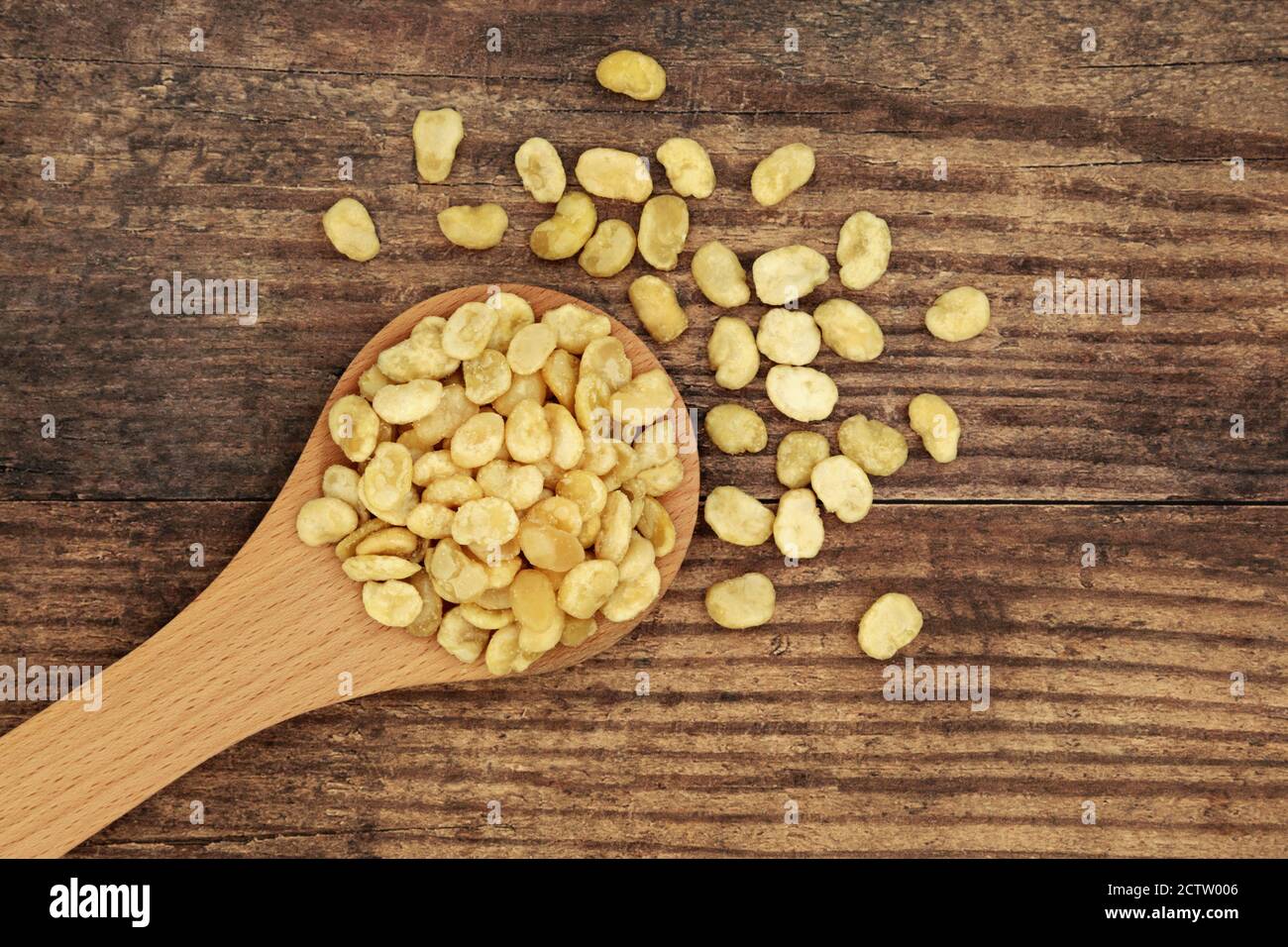 Fava arrosto fagioli per un sano vegan & cibo vegetariano snack in un cucchiaio di legno e sciolto su sfondo rustico legno. Alto in proteine, vitamine, dietetica Foto Stock