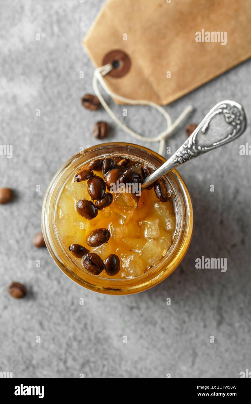 marmellata di frutti di pera di winh piatto con chicchi di caffè. Vasetto di confettura di pere su fondo grigio di cemento. Minimalismo Foto Stock