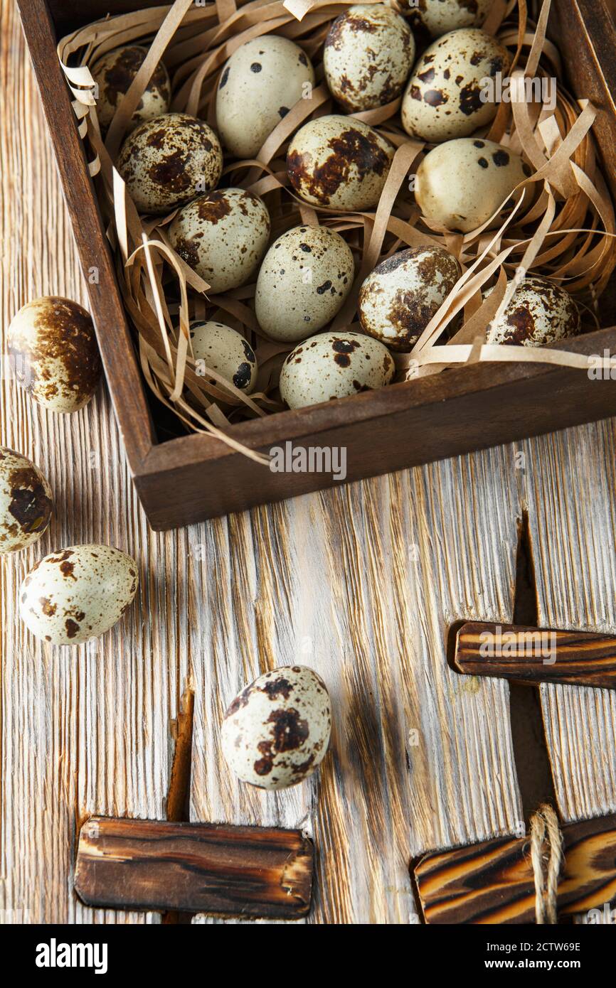 Uova di quaglia. Composizione piatta con piccole uova di quaglia sullo sfondo naturale di legno. Un uovo rotto con un tuorlo luminoso. Fattoria uova Quail Foto Stock