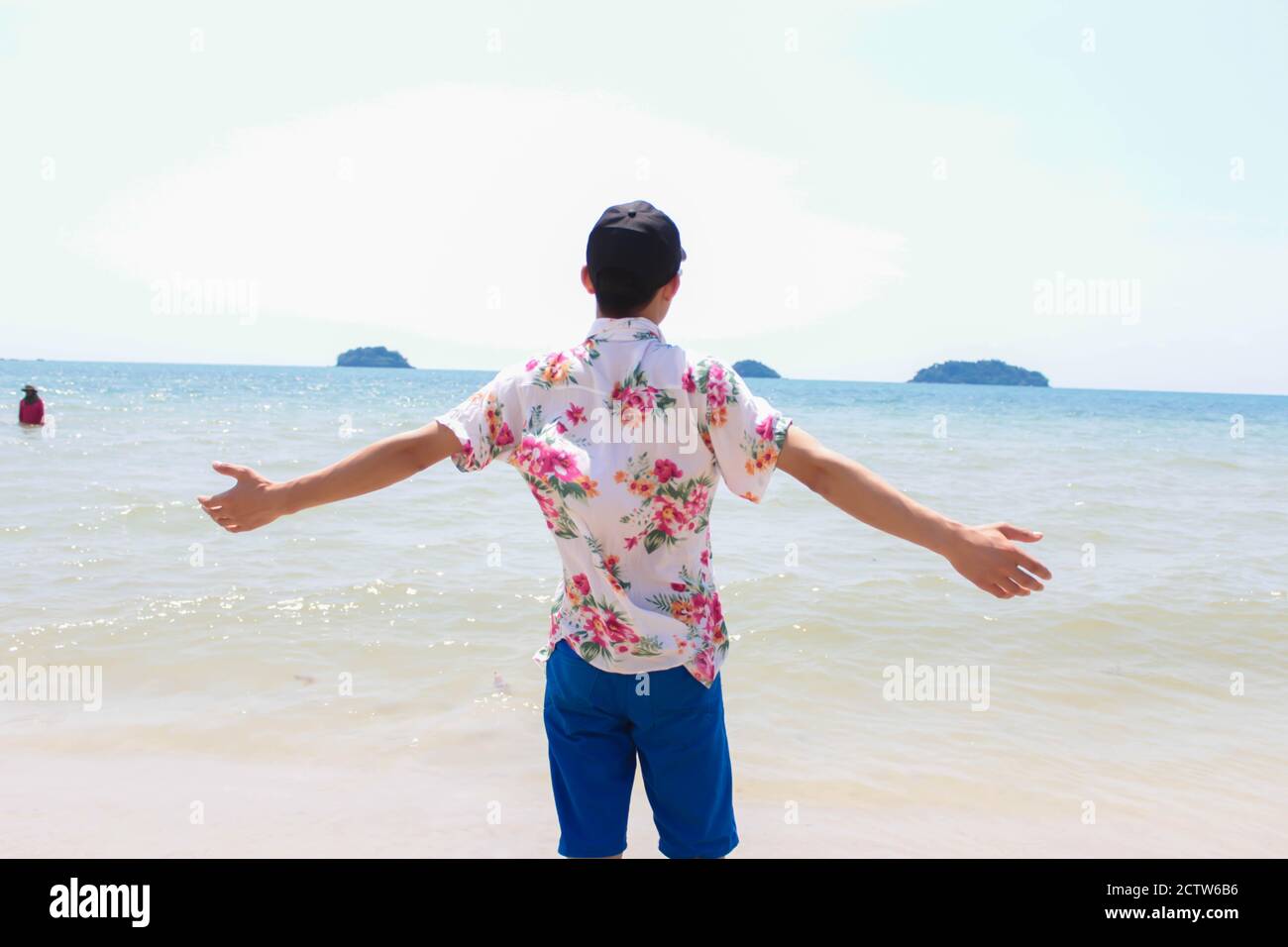 L'uomo solitario si erge sulla spiaggia guarda verso il sole leggero Foto Stock