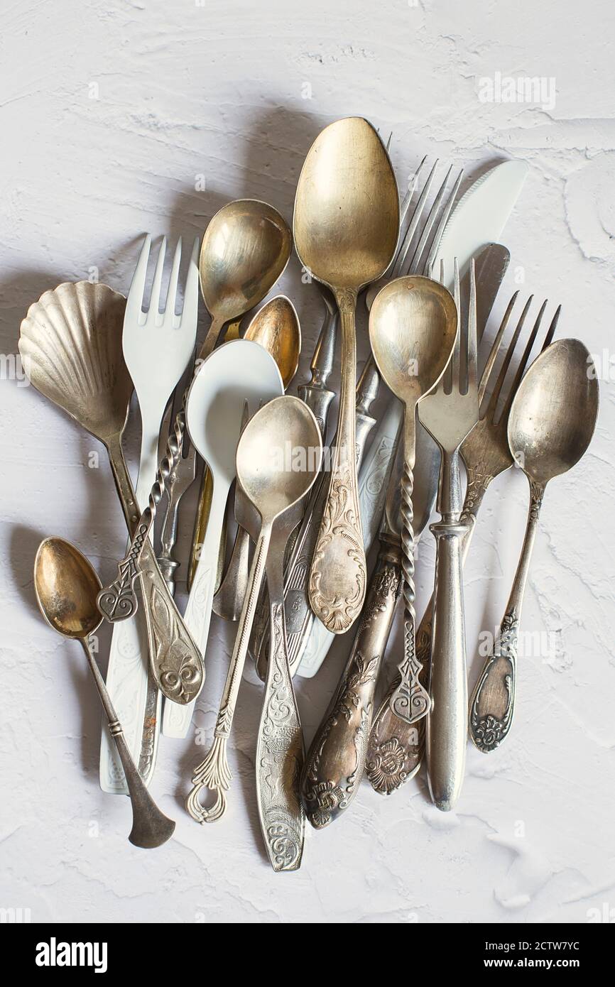 Posate vintage su sfondo bianco. Cucchiai, forchette e coltelli da tavolo in argento e cupronickel. Foto Stock