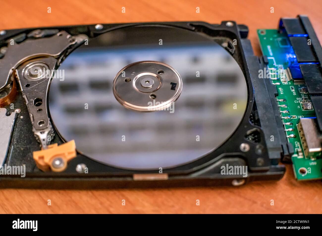 Il disco rigido è adagiato sul tavolo, lampeggia e ruota il disco. Lavoro di un disco rigido hacked all'interno. Sicurezza del computer. Struttura interna di Foto Stock
