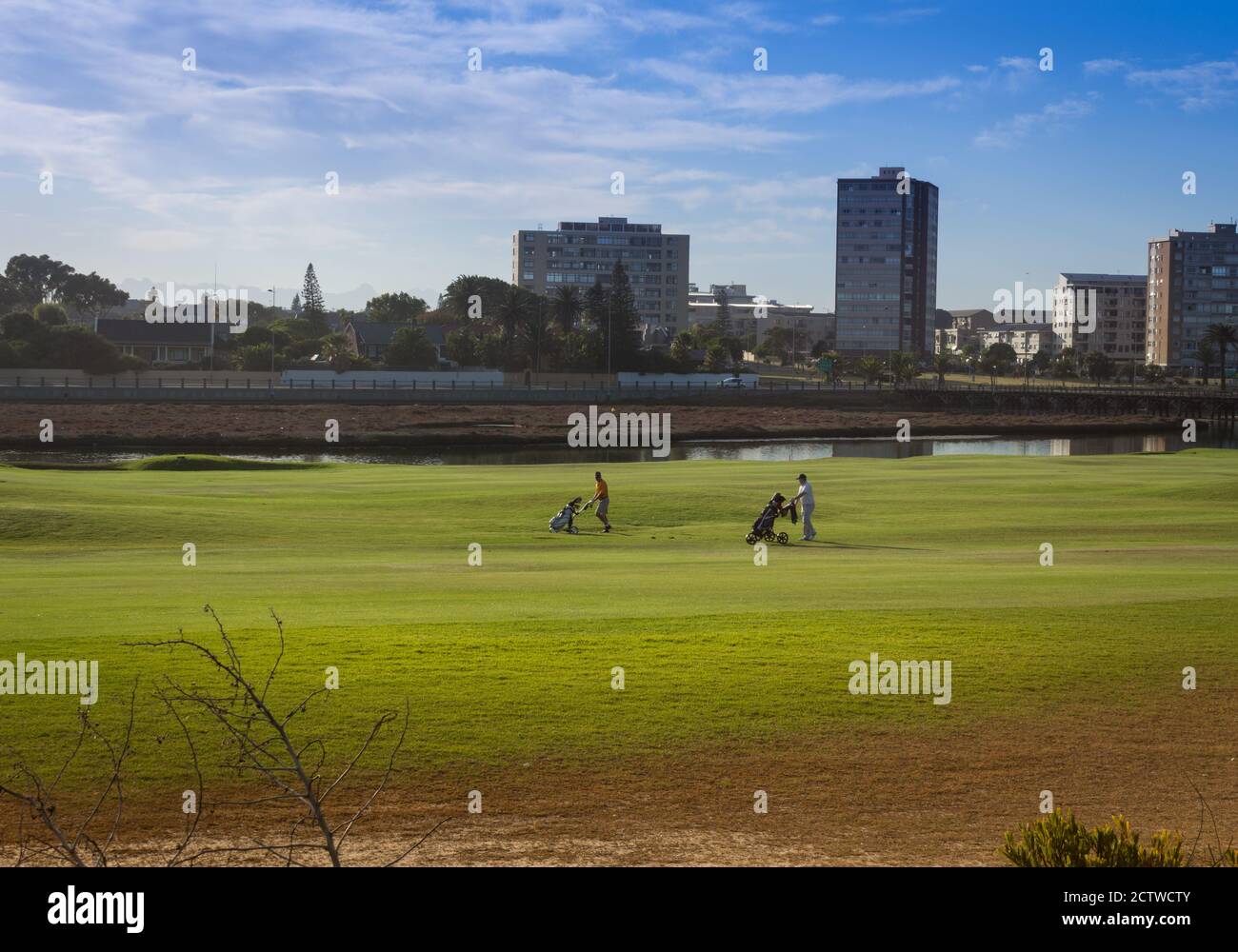 I golfisti giocano a golf su un prato verde con una laguna sullo sfondo, Città del Capo, Sud Africa Foto Stock