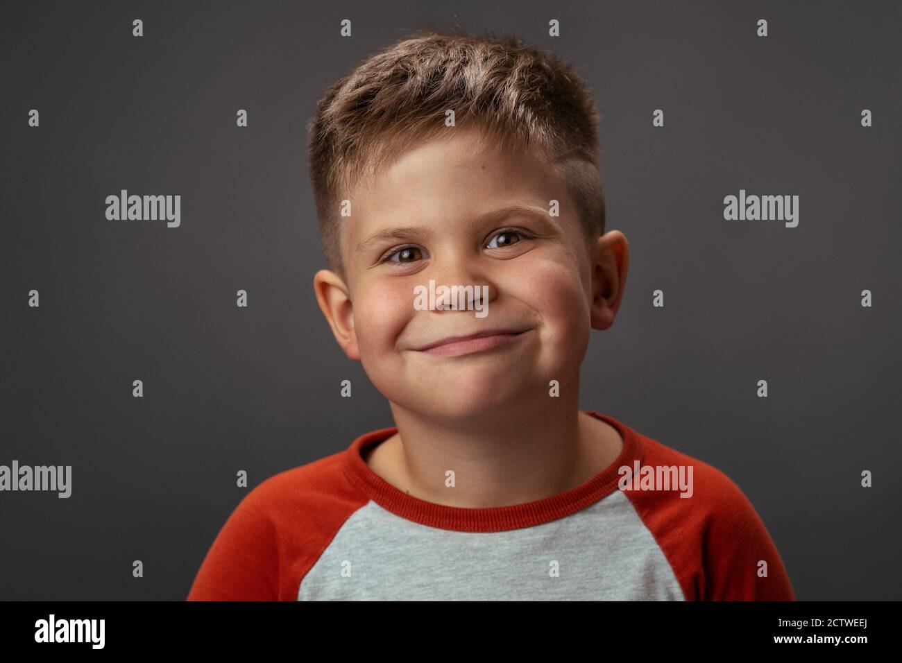 Ragazzo divertente sorride alla macchina fotografica in studio. Ritratto di un bambino sorridente. Foto di alta qualità Foto Stock