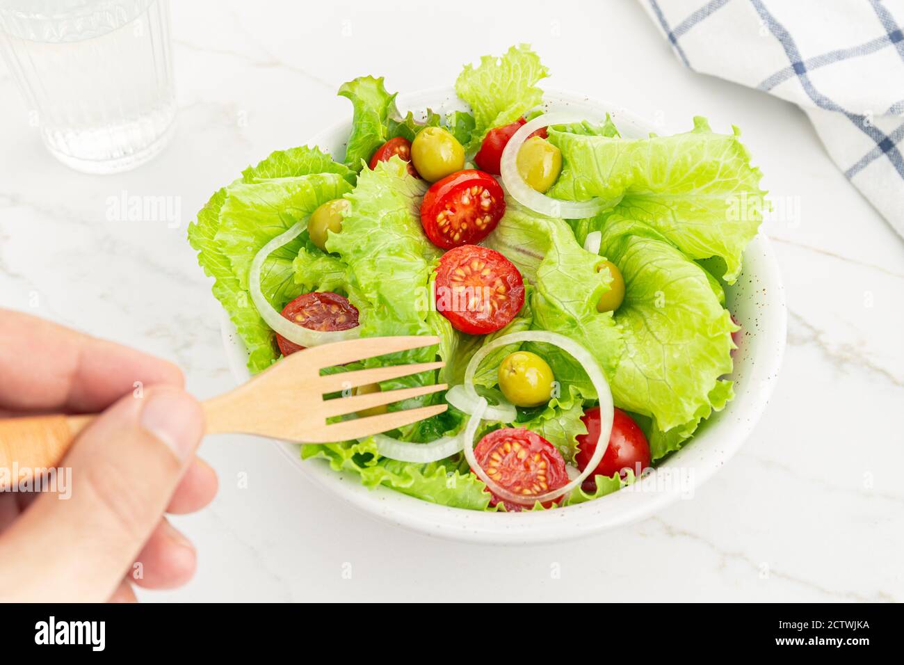 Mano di un uomo che mangia un'insalata fresca e sana in una ciotola. Cucina mediterranea Foto Stock