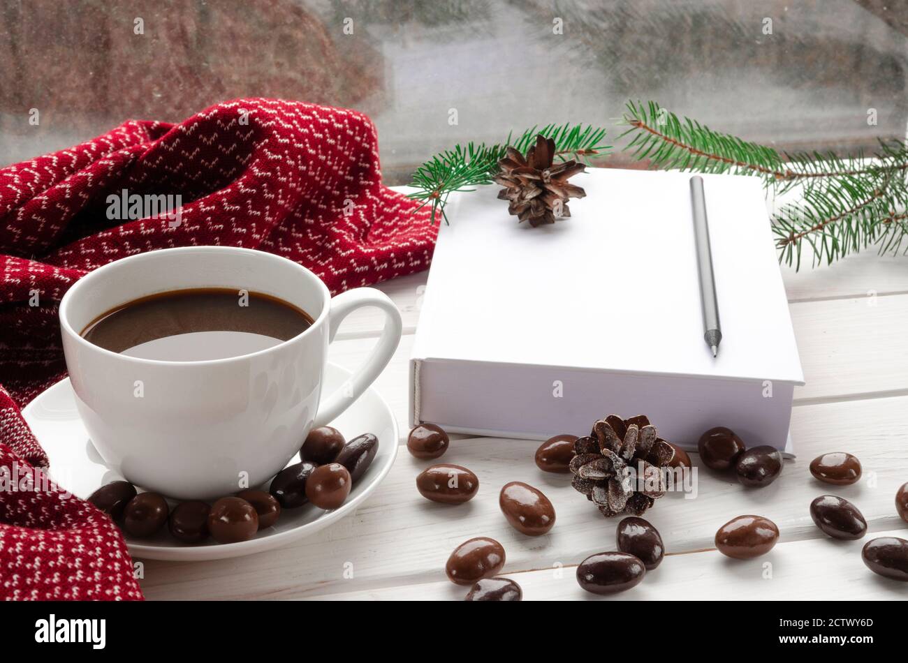 Tazza di caffè bianco con cioccolatini su un bianco soglia del finestrino contro il finestrino Foto Stock