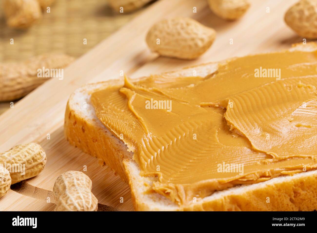 Delizioso panino di burro di arachidi su sfondo di legno con arachidi Foto Stock