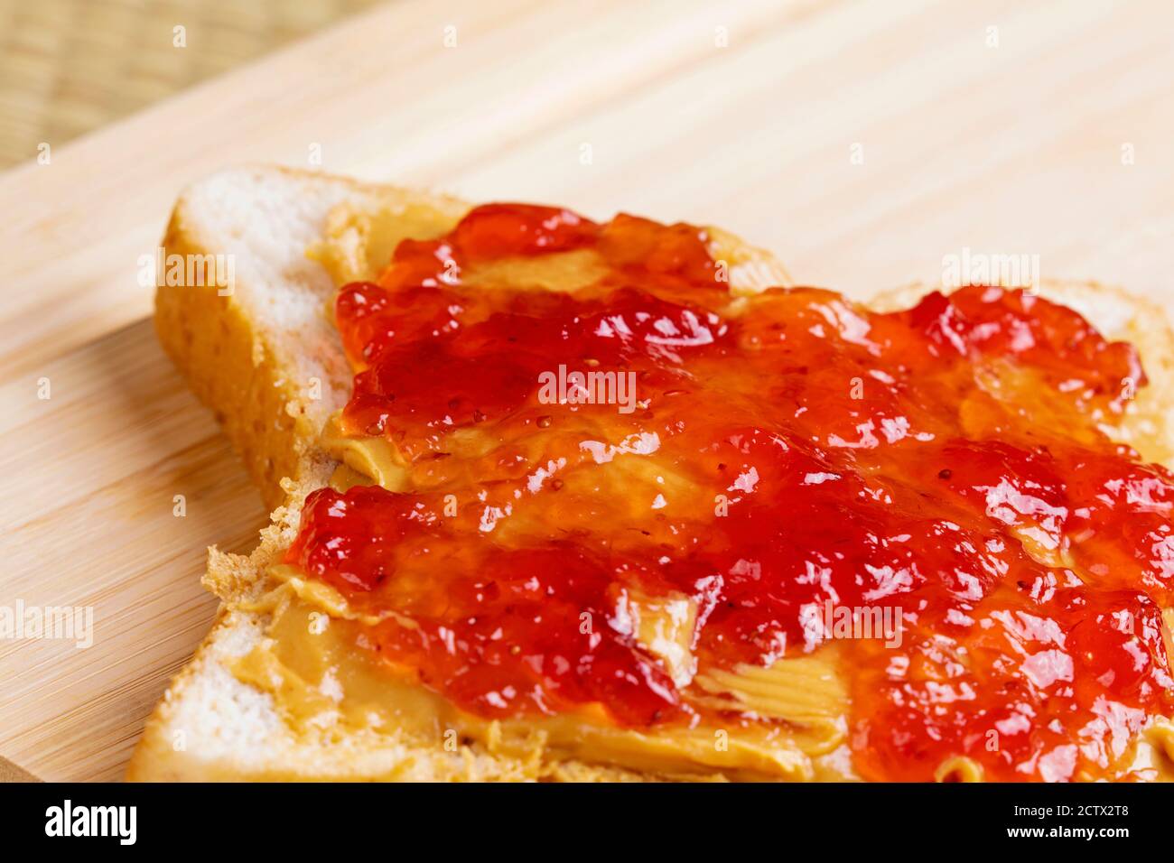 Un gustoso e delizioso panino di burro di arachidi e marmellata su un sfondo di legno Foto Stock