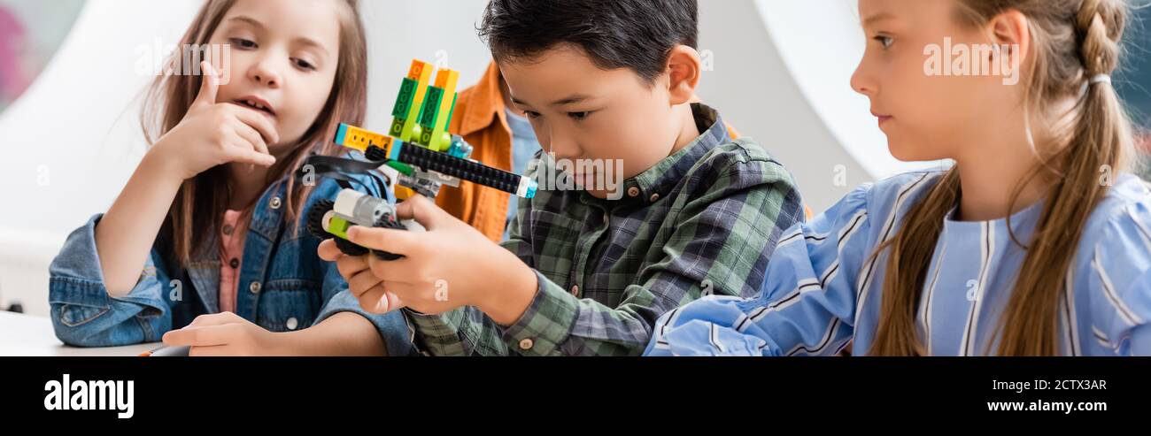 Panoramica di studenti multiculturali che guardano il robot in STEM scuola Foto Stock