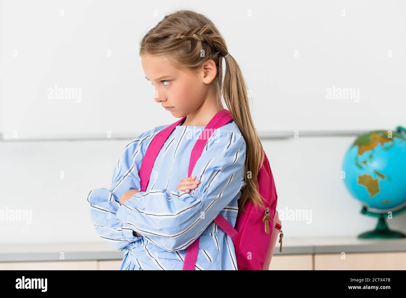 Studentessa seria con zaino che guarda via in classe Foto Stock