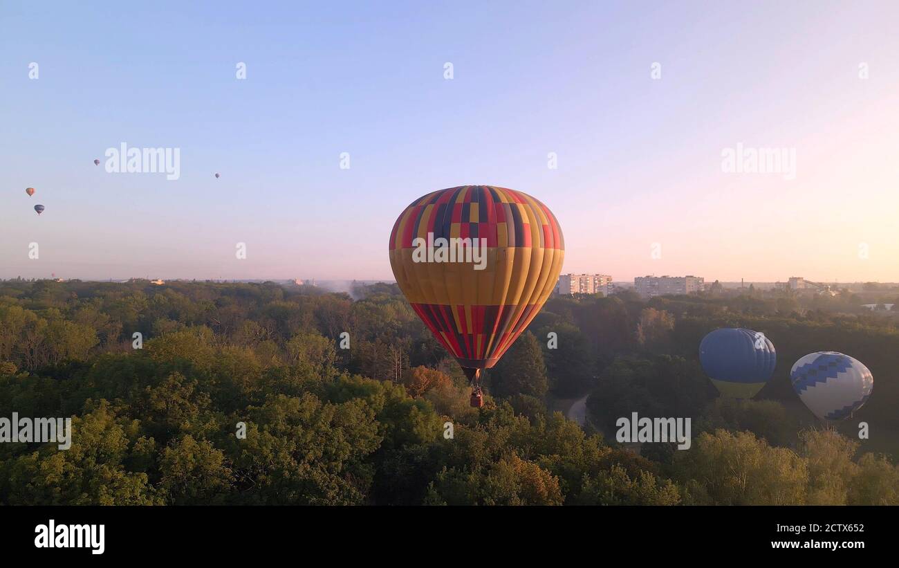 Vista aerea del drone della mongolfiera colorata che sorvola il parco verde nella piccola città europea all'alba estiva, nella regione di Kiev, Ucraina Foto Stock