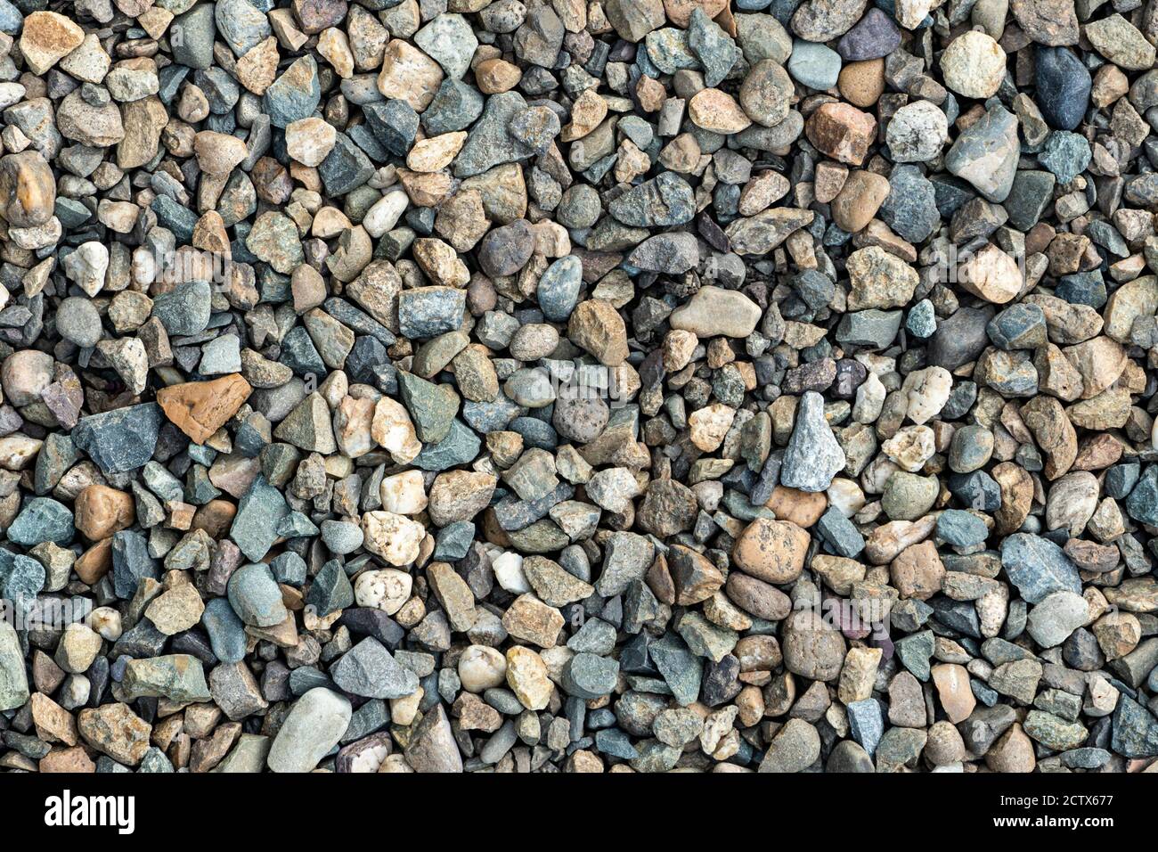 trama ghiaia sullo sfondo. Piccoli ciottoli colorati. Pietre piccole, rocce piccole, ciottoli in molte sfumature di grigio, bianco, marrone, giallo Foto Stock