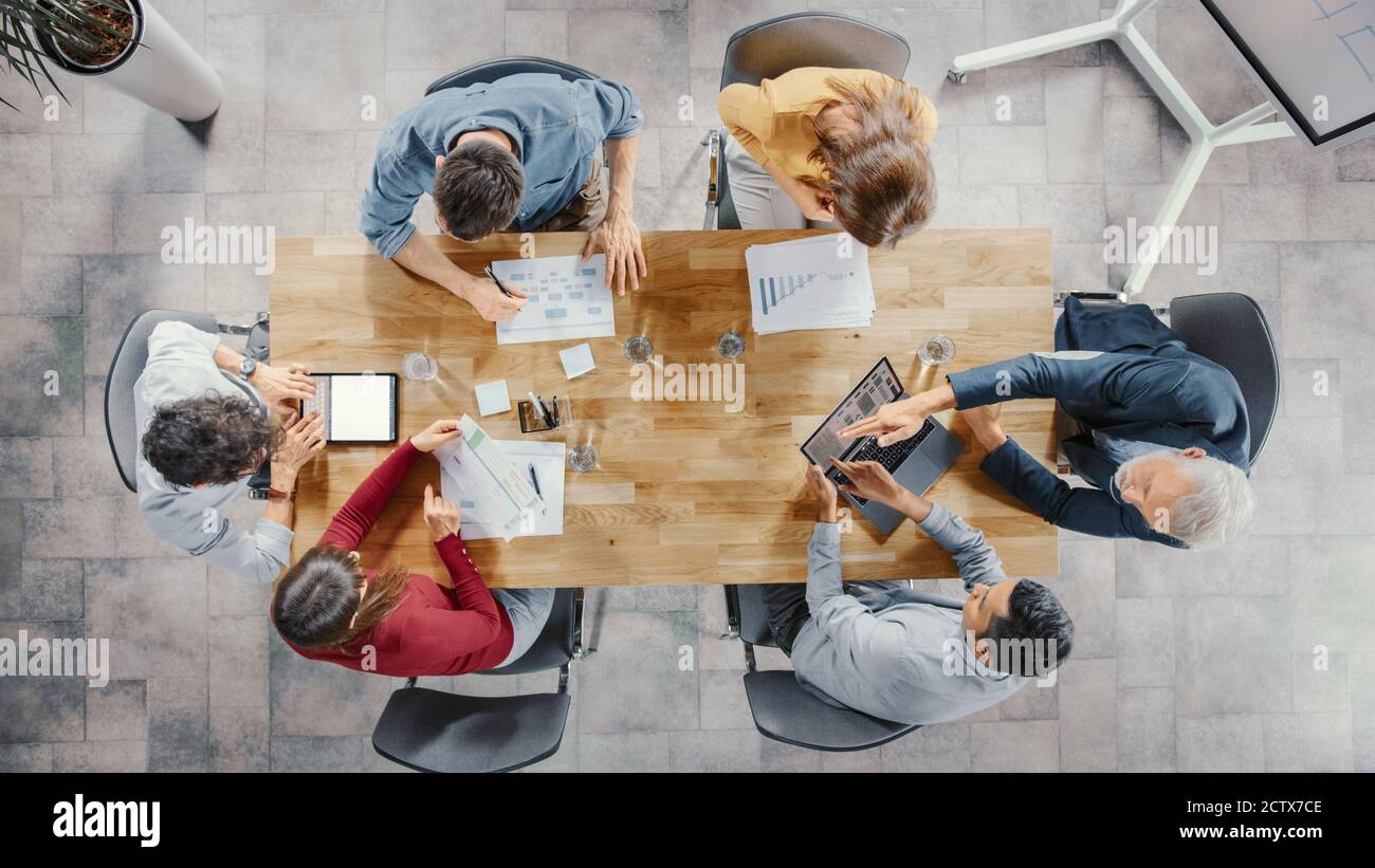 Sala riunioni Startup: Team di imprenditori seduti al tavolo della conferenza hanno discussioni, risolvere problemi, utilizzare Digital Tablet, laptop, condividere Foto Stock