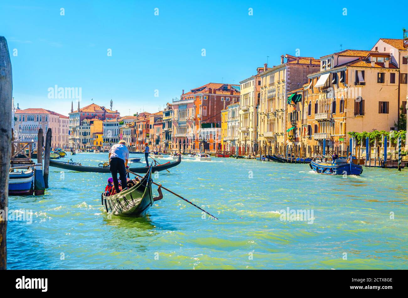 Venezia, Italia, 13 settembre 2019: Gondoliere e turisti in gondola tradizionale barca a vela sulle acque del Canal Grande con architettura veneziana tipici edifici colorati sfondo Foto Stock
