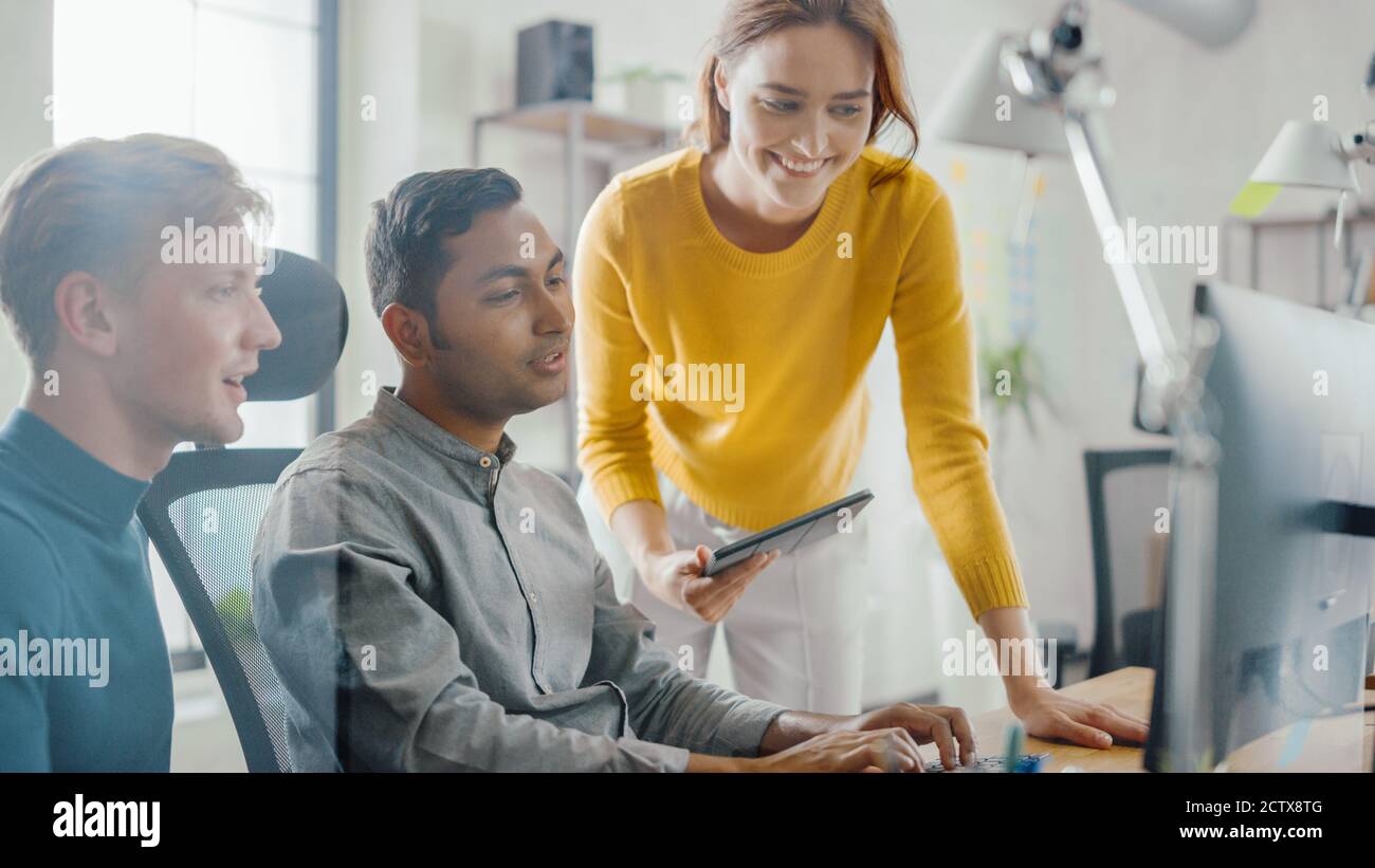 Imprenditore di talento che lavora sul suo computer desktop con Project Manager e Team leader in piedi accanto a lui, hanno discussione, trovare il problema Foto Stock