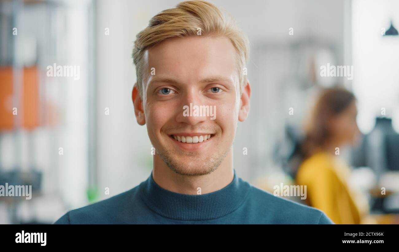 Ritratto di bell'uomo caucasico professionista guardando la fotocamera e sorridendo incantato. Blonde Man di successo che lavora in un ufficio luminoso e diversificato. Foto Stock