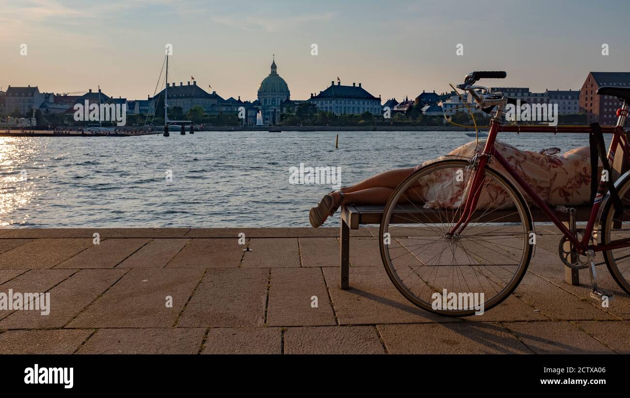 Una giovane donna che ha una pausa al tramonto estivo a Copenaghen Foto Stock