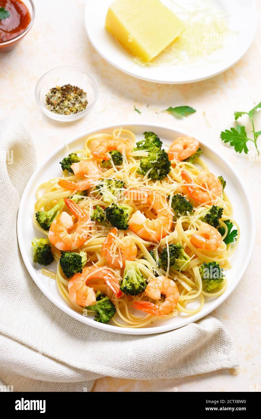 Gamberi e broccoli su piatto su fondo di pietra chiaro. Piatto gustoso per la cena. Foto Stock