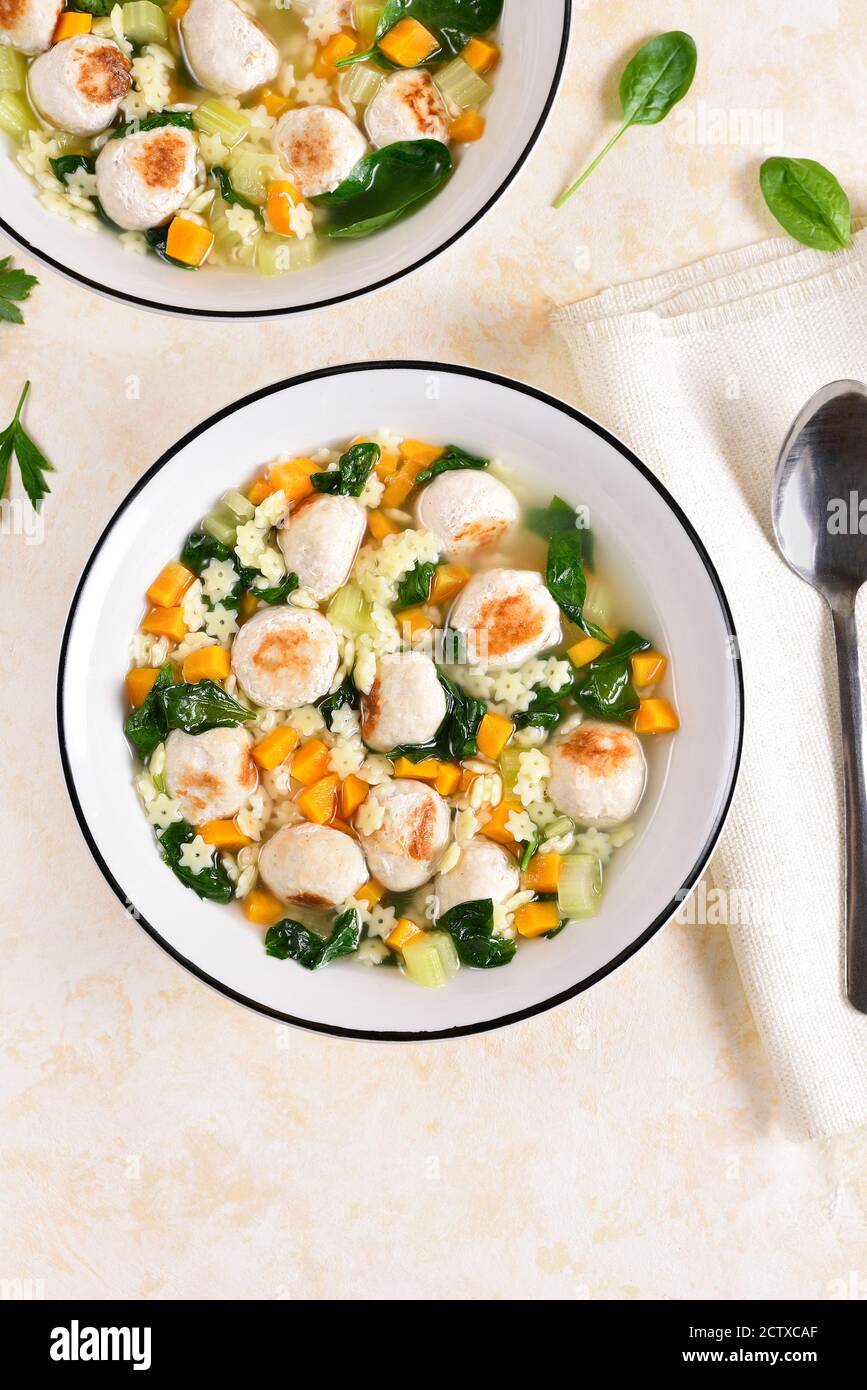 Zuppa italiana di nozze con polpette, verdure e piccola pasta in ciotola su fondo di pietra chiaro. Piatto di dieta sana per cena. Vista dall'alto, disposizione piatta Foto Stock