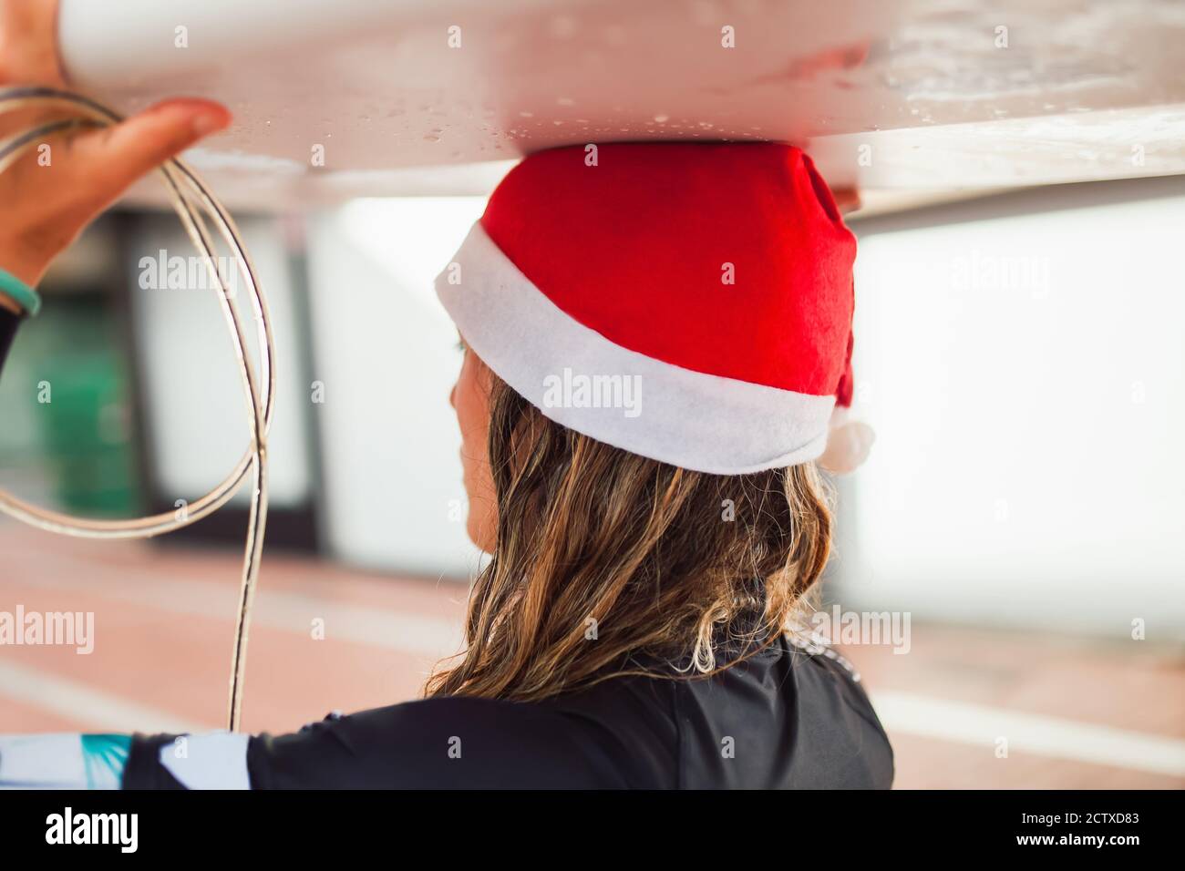 Attraente istruttore di surf donna che cammina con la sua tavola da surf lungo il lungomare Foto Stock