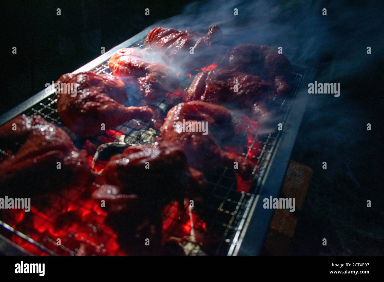 Cene a base di pollo alla griglia: Barbecue affumicato per feste invernali. barbecue in spiaggia di sera. Cottura con pollo alla griglia Foto Stock