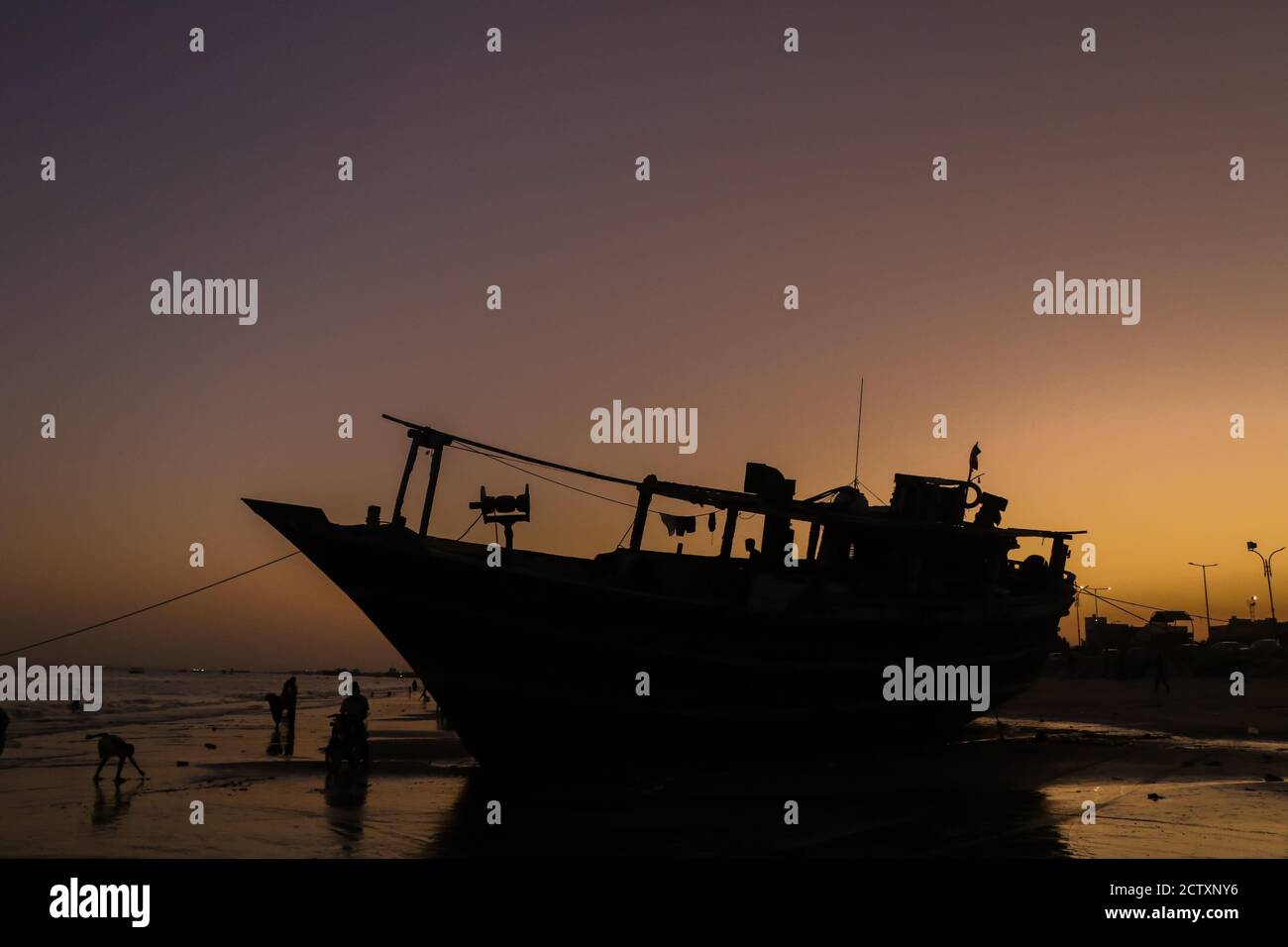 Due marinai che lavorano sulla loro barca presso la spiaggia dell'Iran meridionale Foto Stock