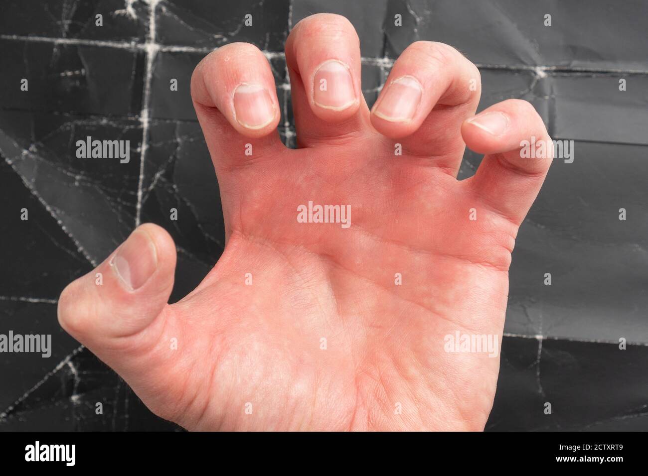 L'uomo gli afferrò la mano in cupidigia e rabbia da vicino. Su uno sfondo drammatico di carta nera sbriciolati Foto Stock