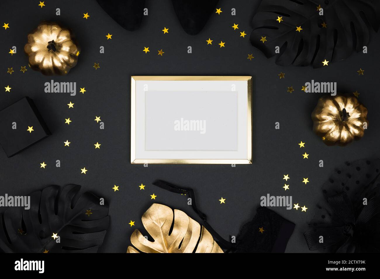 Halloween party collection accessori outfit femminile su sfondo nero: cappello con velo, cintura garter, regali. Zucche nere e dorate, piatto, top Foto Stock