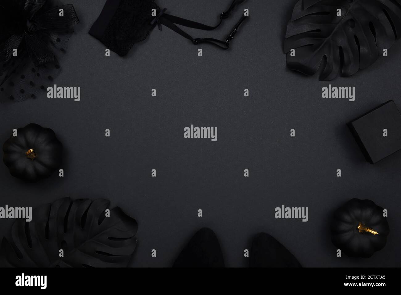 Halloween party collection accessori outfit femminile su sfondo nero: cappello con velo, cintura garter, regali. Zucche nere e dorate, piatto, top Foto Stock
