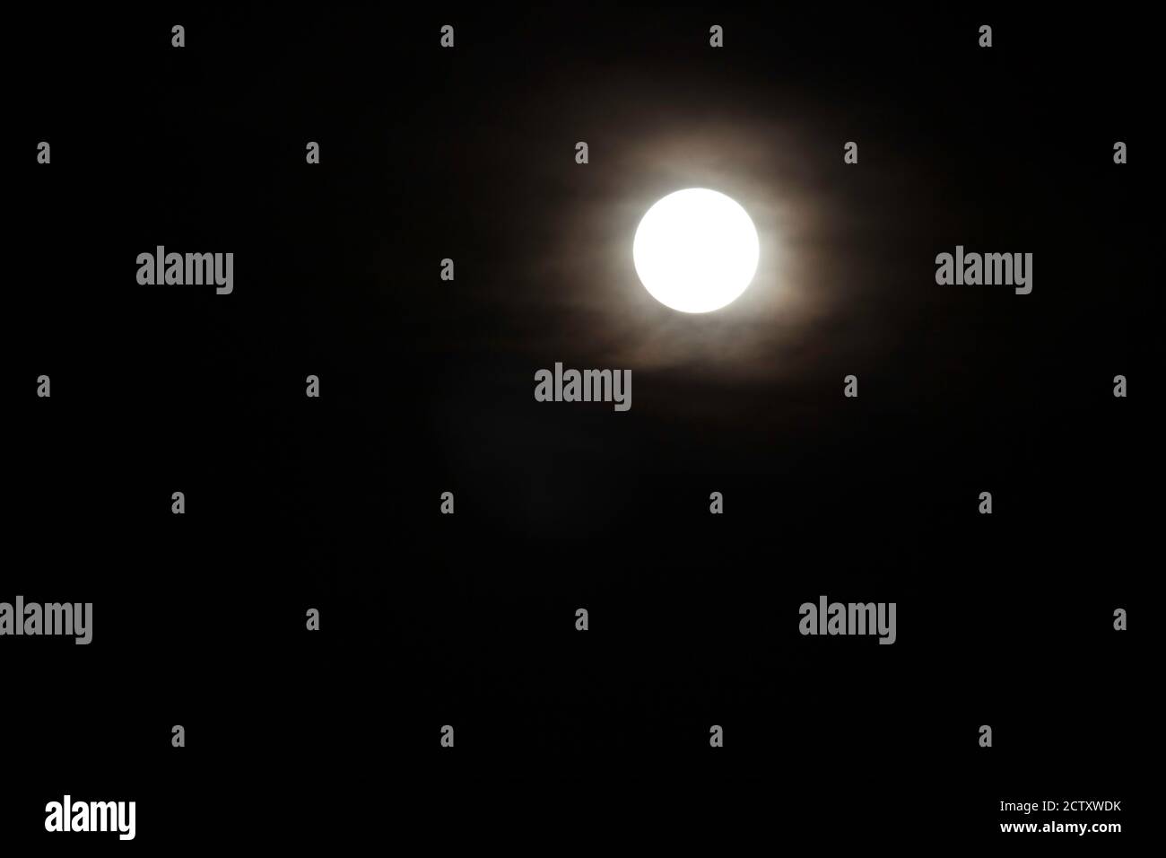La luna piena che splende attraverso la copertura nuvolosa Foto Stock