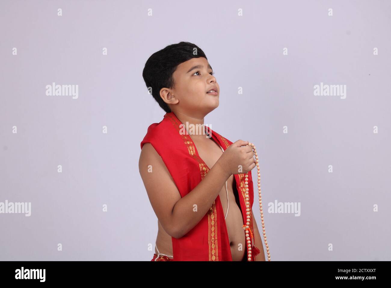 Ragazzo carino in indiano etnico indossare canti nome di Dio / jaap. Utilizzando una stringa di rosario di perle di preghiera o japamala. Foto Stock