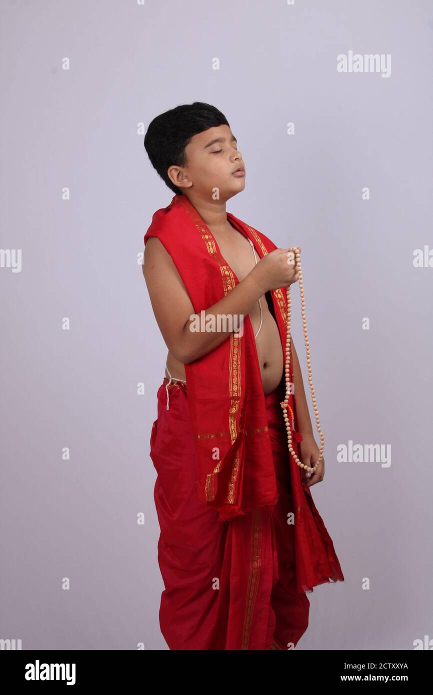 Ragazzo carino in indiano etnico indossare canti nome di Dio / jaap. Utilizzando una stringa di rosario di perle di preghiera o japamala. Foto Stock