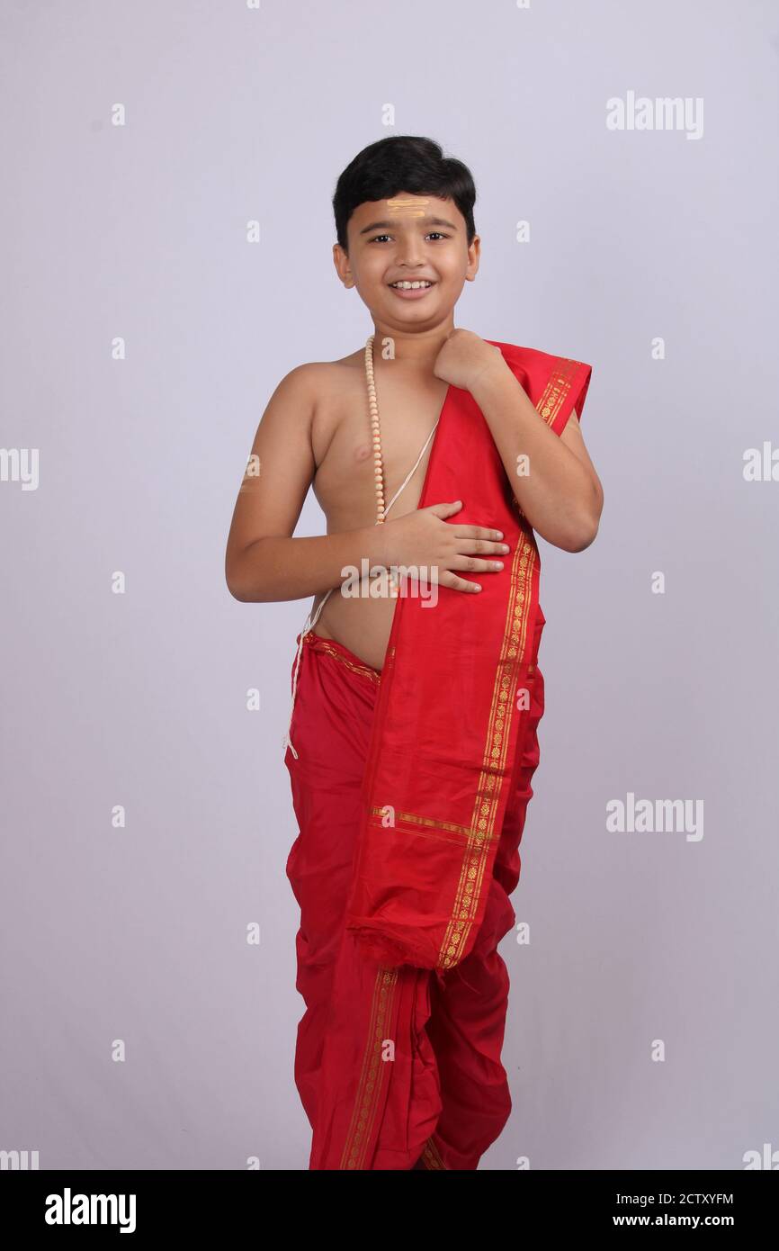 Carino ragazzo indiano in abito etnico svla e uparna - dhoti e stole. Tenendo la sua stola. Foto Stock