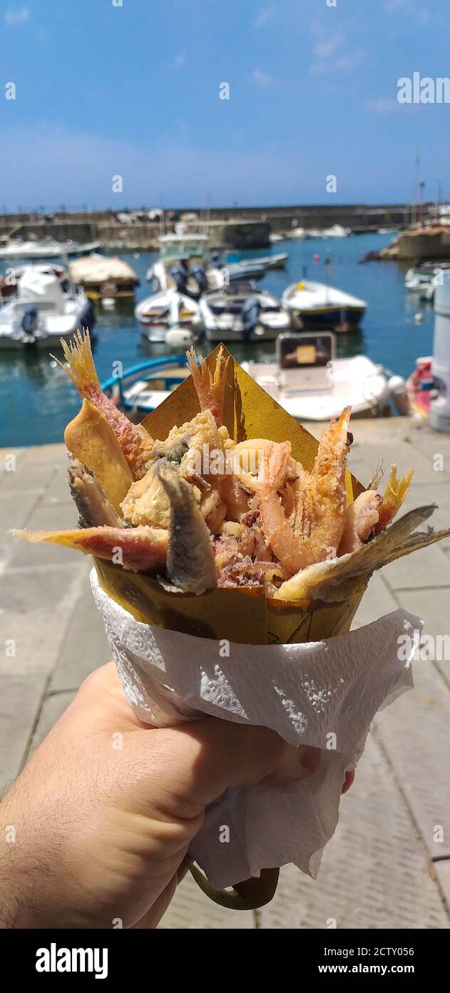 Cibo di strada, pesce fritto cotto sulla barca e mangiato sul molo del porticciolo di Camogli in Liguria. Foto Stock