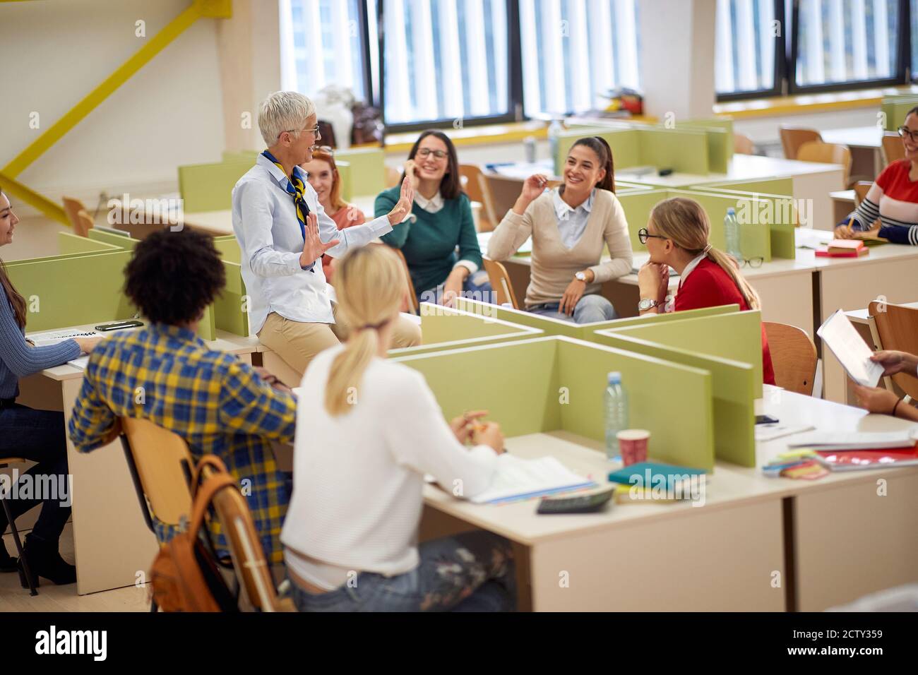 Docente femminile e studenti in una conferenza in un'atmosfera rilassata in classe Foto Stock