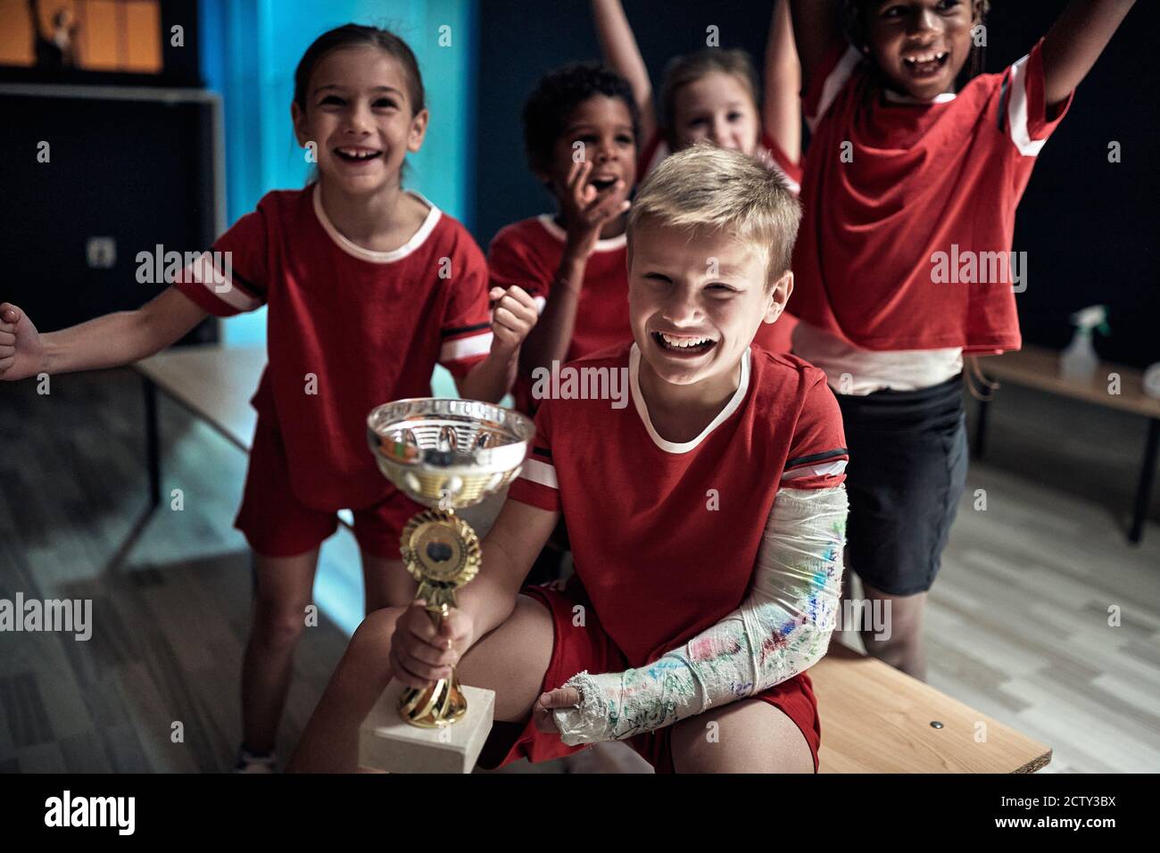 I piccoli giocatori di calcio in un armadietto sono eccitati sulla vittoria Foto Stock