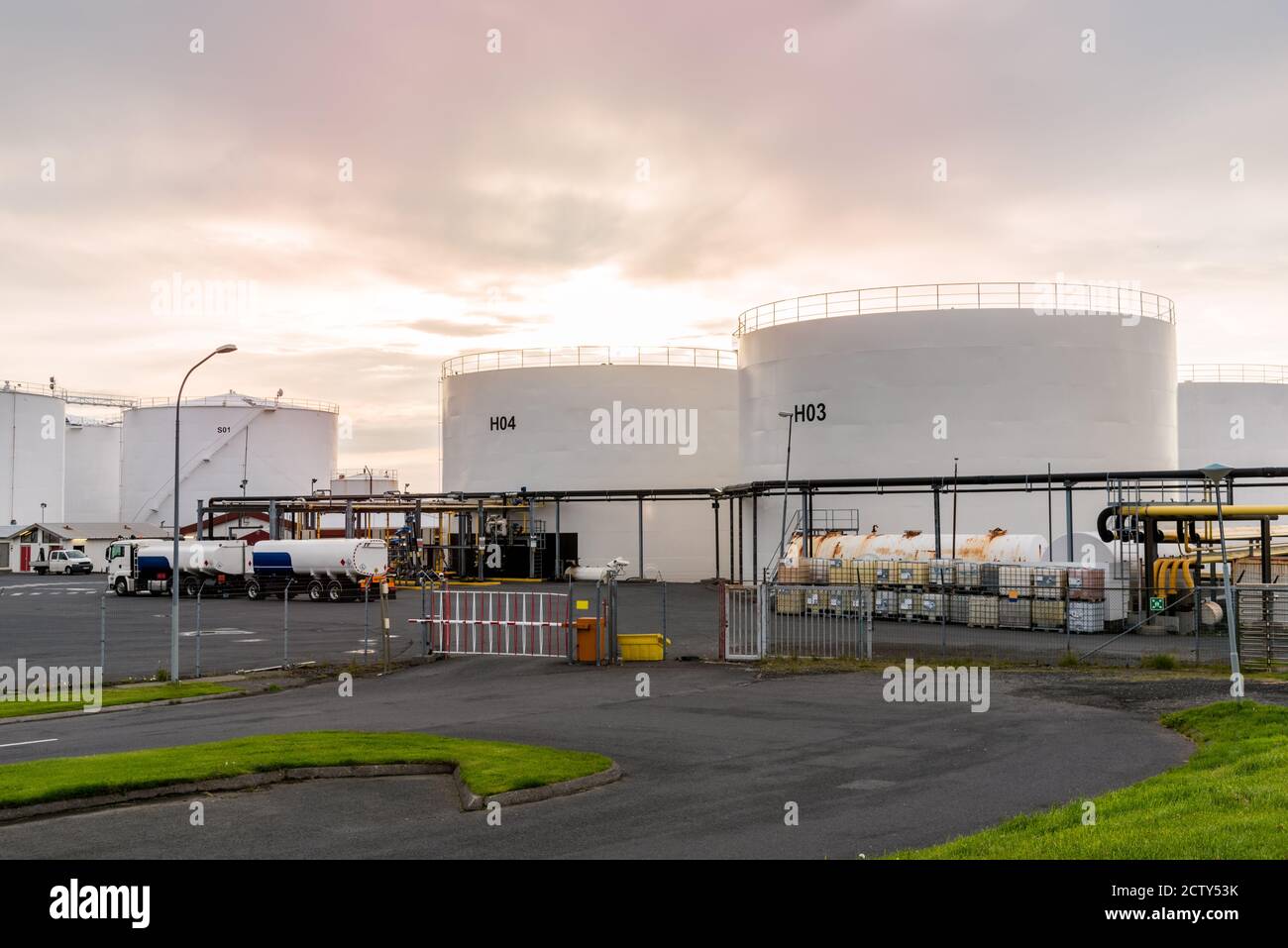 Enormi serbatoi di carburante bianchi in un porto al tramonto Foto Stock