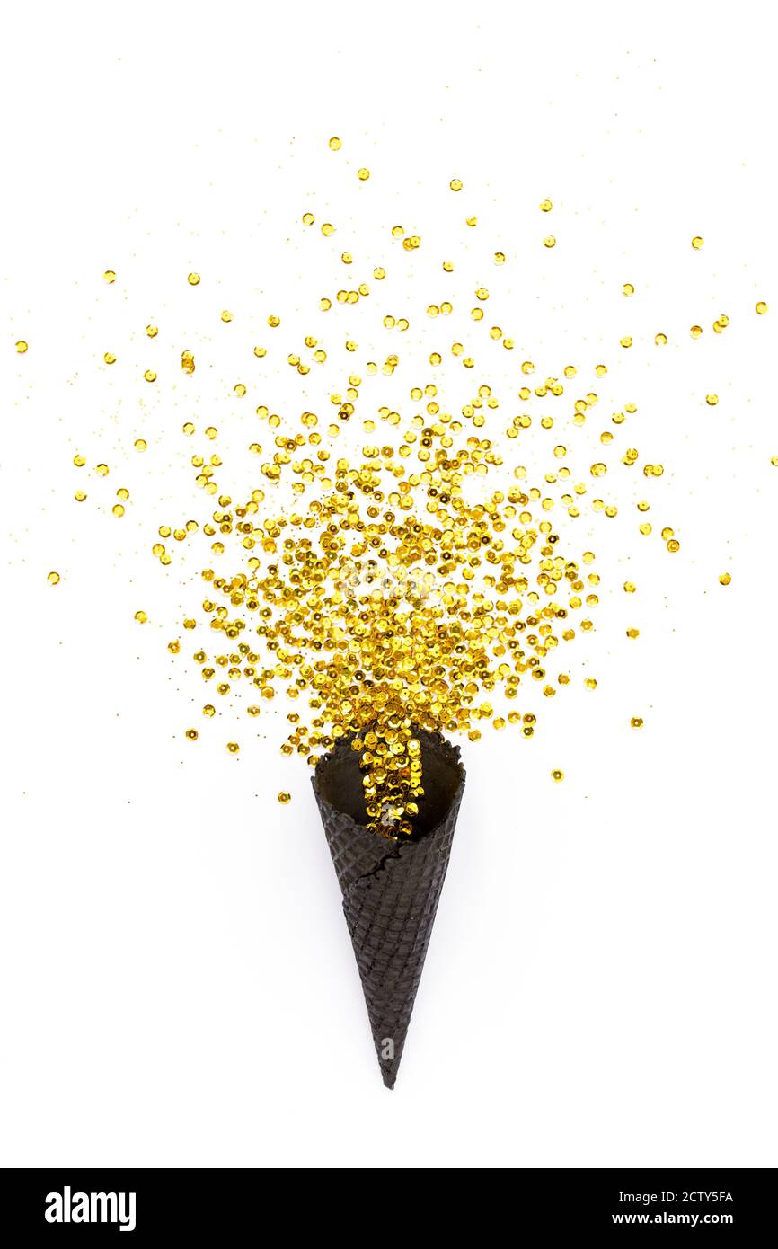 Coni di cialda neri con spoletta di confetti dorati isolati su sfondo bianco. Disposizione piatta, vista dall'alto, concetto di festa minimo. Foto Stock