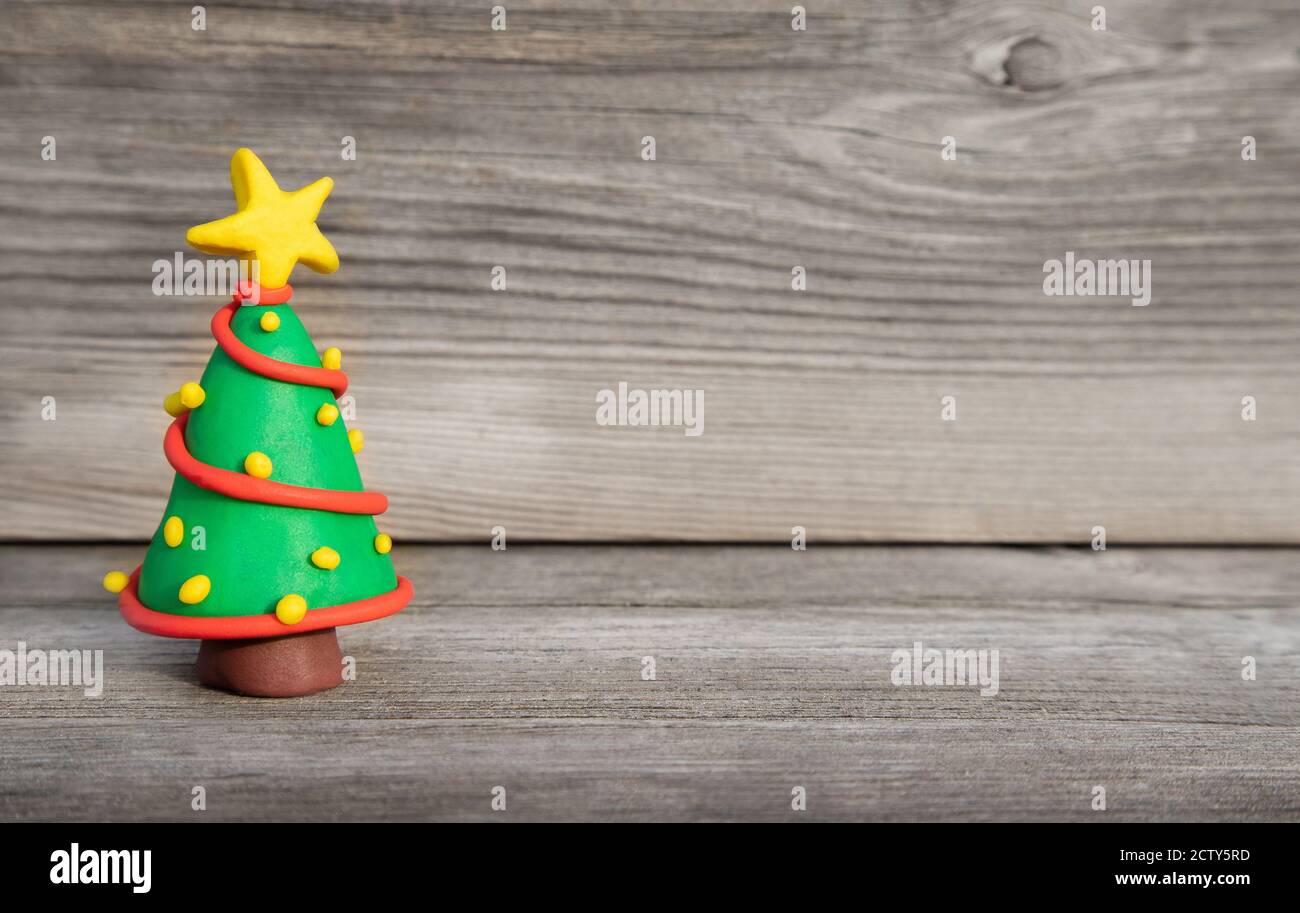 Allegro Natale concetto di argilla. Colorato albero di Natale in miniatura fatto a mano per Natale di fronte a legno morbido sfondo. Spazio di copia. Foto Stock