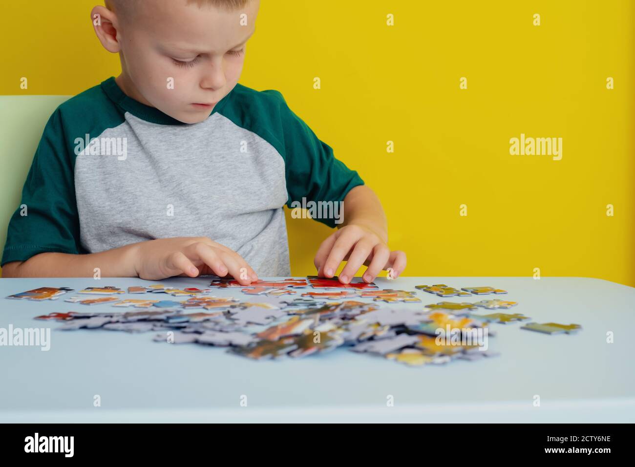 Il capretto che fa i puzzle. Il concetto dei giochi educativi della scheda. Foto Stock