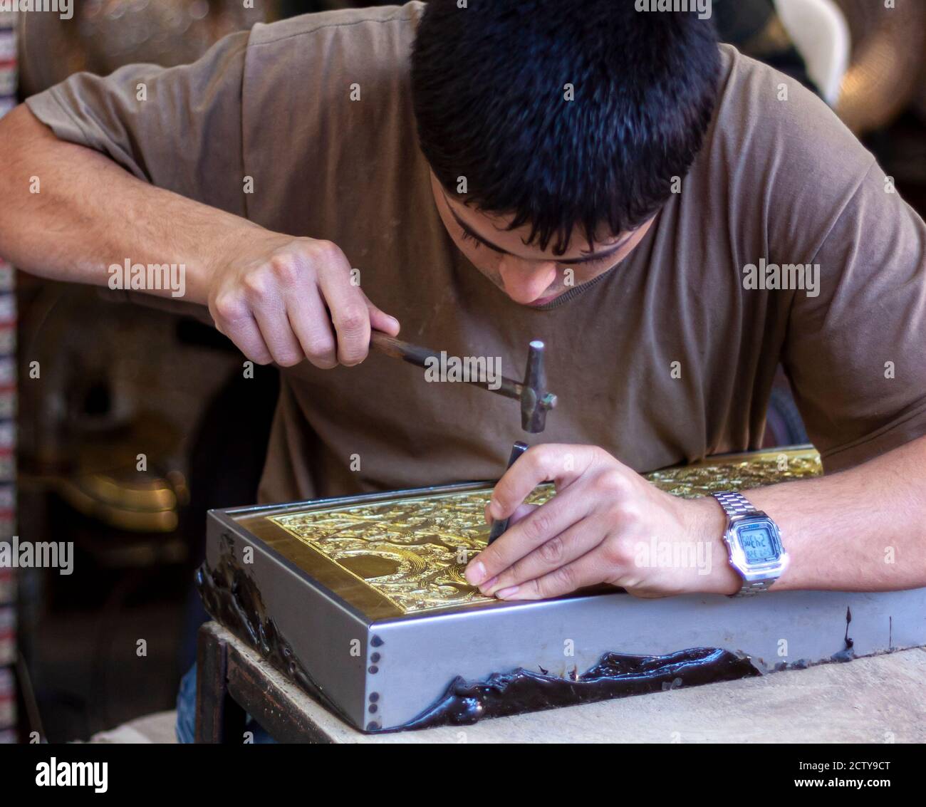 Damasco ,Siria 03/27/2010: Primo piano immagine di un giovane artista al lavoro. Sta intagliando con cura una piastra di rame con decorazioni tradizionali usando un martello Foto Stock