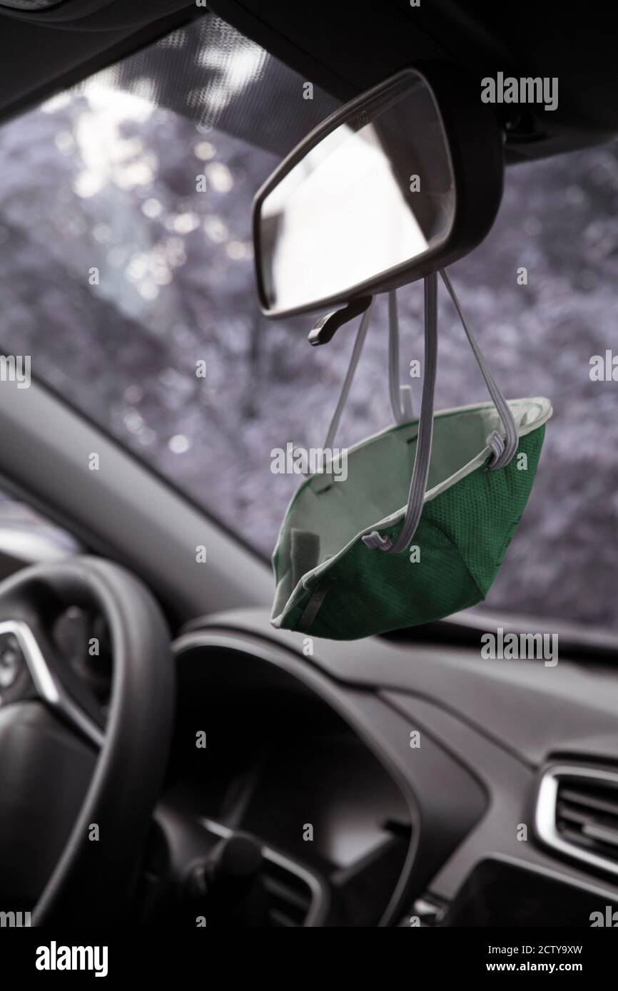 La nuova normale: Una maschera medica viso è fissata al finestrino posteriore di un'auto per un comodo accesso al riutilizzo secondo necessità, una soluzione creativa durante Foto Stock